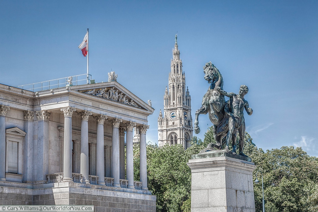 The Horse Tamer statue is one of a pair flanking the entrance to the parliament buildings.  The Rathaus clock tower features in the background, Vienna, Austria