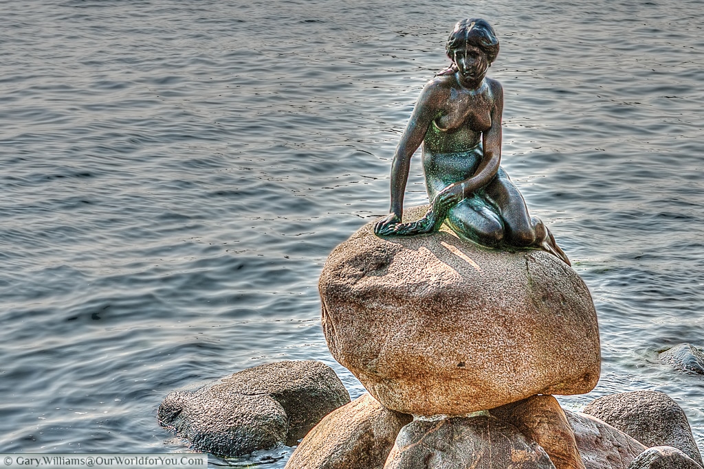The Little Mermaid sits perched on a rock in the waterside at the Langelinie promenade, Copenhagen, Denmark