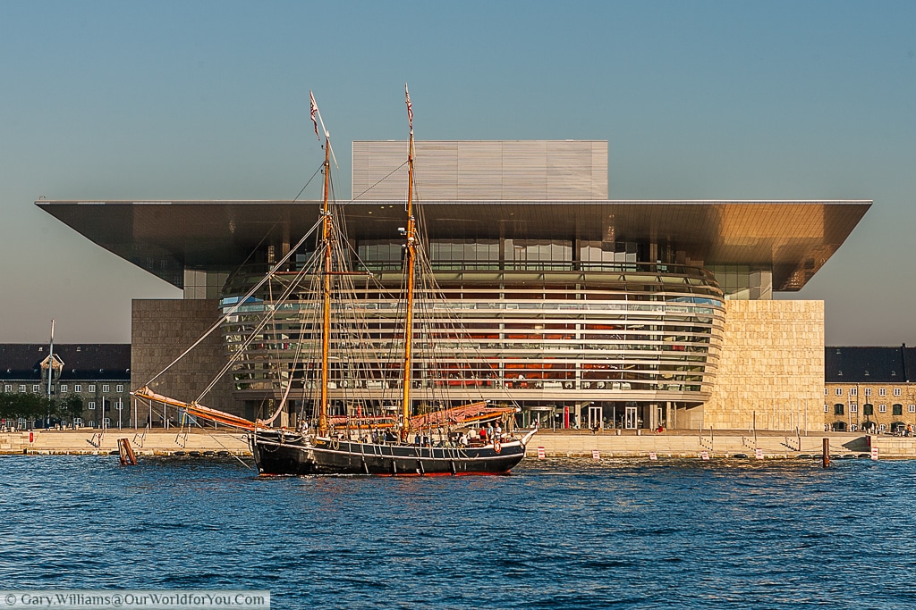 A sail boat floats in front of the Copenhagen Opera House, Copenhagen, Denmark