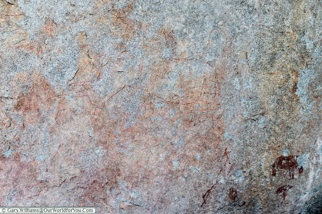 The faint outline of a rhino in a cave painting.