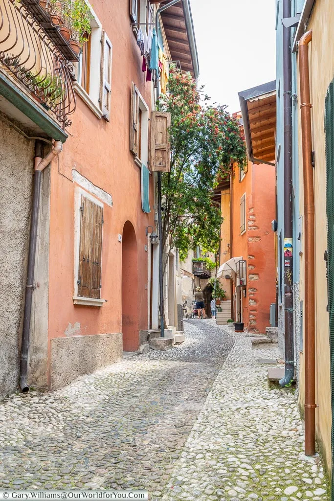 A cobbled lane lined on each side with ochre-coloured buildings.