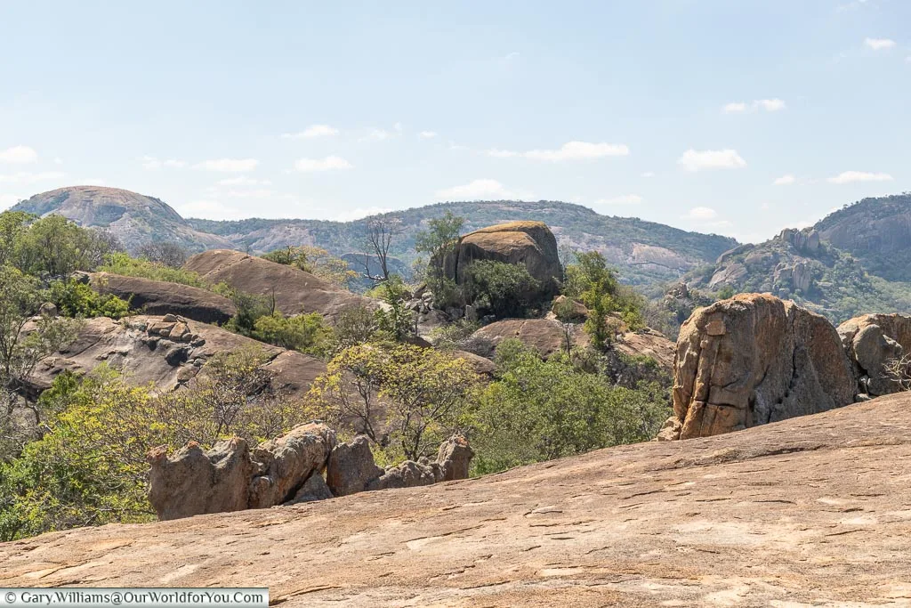 A view of a collection of boulders from the top of another rock formation.