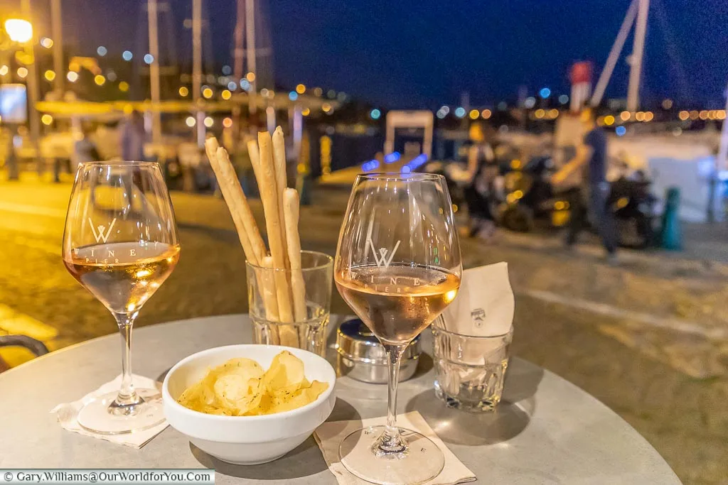 Two glasses of rosé wine in front of the harbour of Villefranche-sur-Mer at night.