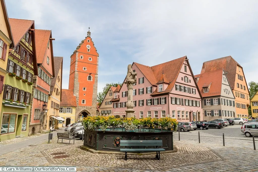 Looking over the Löwenbrunnen fountain with the Wörnitz gate at the base of a tower. All the buildings again are painted in traditional colours.
