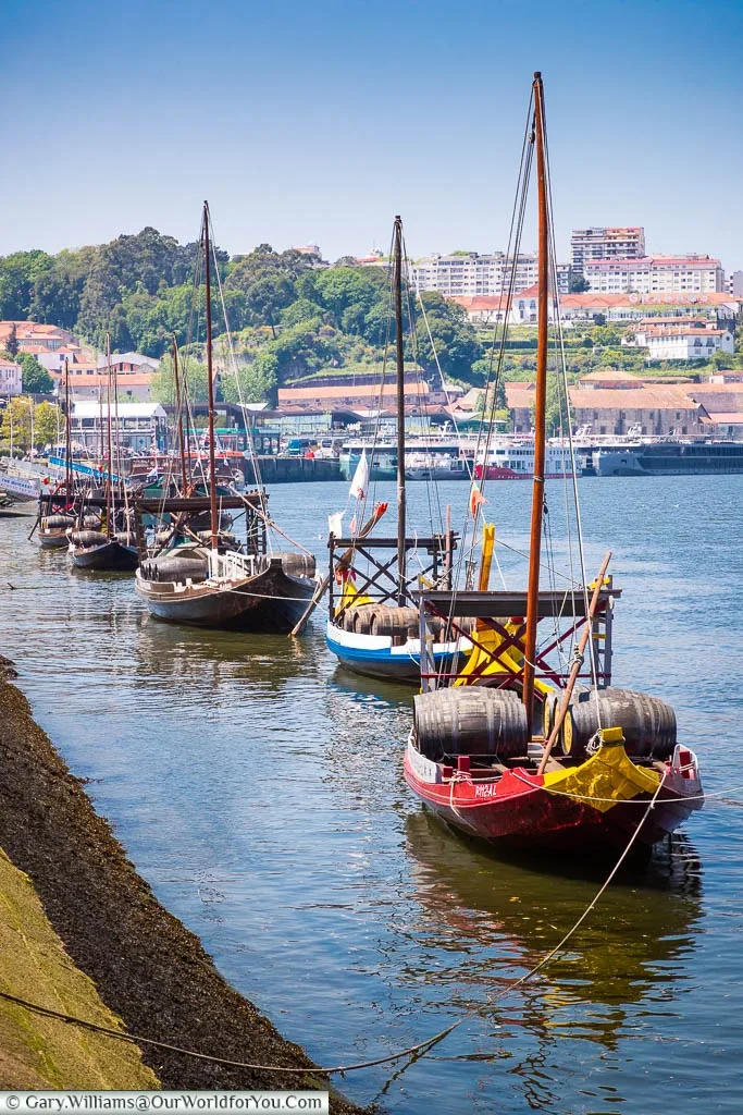 A row of traditional Rabelo sailing boats moored up on the south side of the Douro River in Porto, Portugal