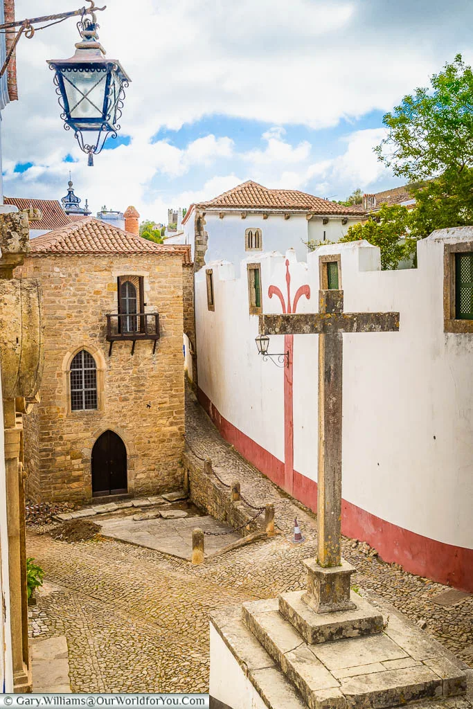 A stone cross in the centre of a tiny medieval square in the old town of Óbidos