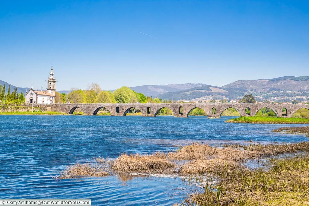 The view along the River Limia to the Roman bridge spanning it at Ponte de Lima in Northern Portugal