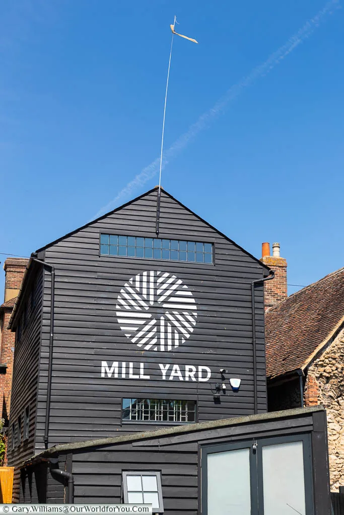 A white-painted sign & logo for Mill Yard on the side of a black weatherboarded grain tower in West Malling, Kent