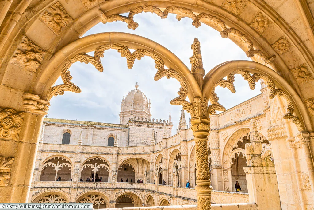 Looking through the stone arched windows within the cloisters the Mosteiro dos Jerónimos to the tower beyond