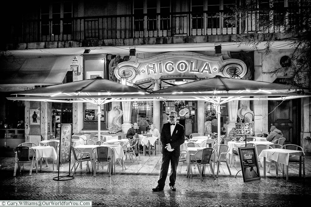A black and white image of the maitre d' standing in front of the Café Nicola in Lisbon, Portugal