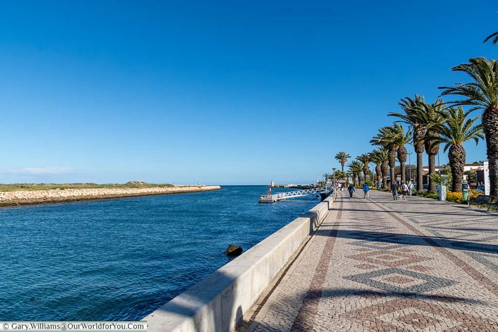 Next to the water the wide, tiled, palm-lined promenade in Lagos, Portugal