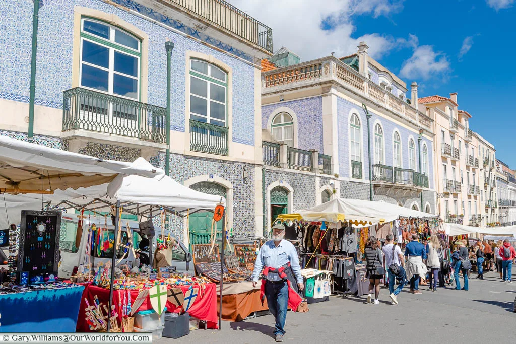 People strolling past market stalls in front of an elegantly tiled buildings in the Thieves Market, Lisbon, Portugal