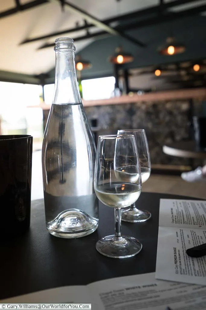 Two glasses of the light coloured Bacchus 2018 vintage in the tasting room accompanied with a bottle of water to refresh the palate.