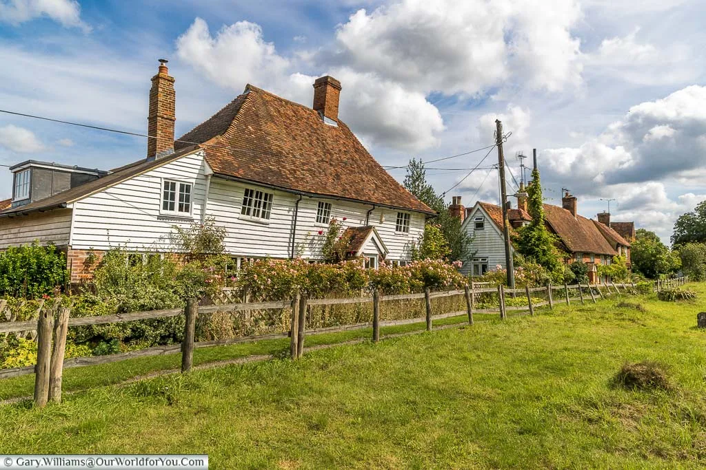 A white timber clad cottage alongside the churchyard on a sunny day