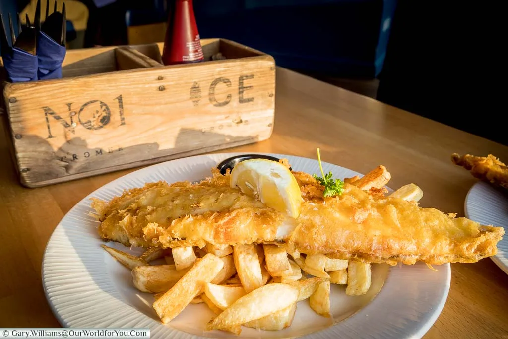 A plate of Fish 'n' Chips at No1, Cromer, with a generous portion of battered cod atop golden chips, garnished with a lemon and a sprig of parsley