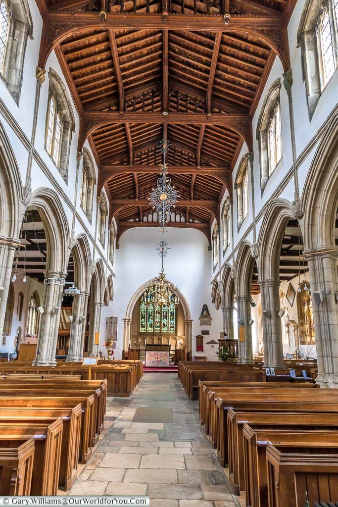 Inside the simple interior of St Dunstan's church. The high vaulted wooden roof catches your eye as you look alone the path between the pews