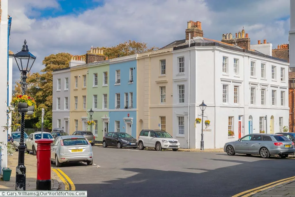 A quaint scene of a block of Georgian three-storey terraced homes, each individually painted in a pastel shade.