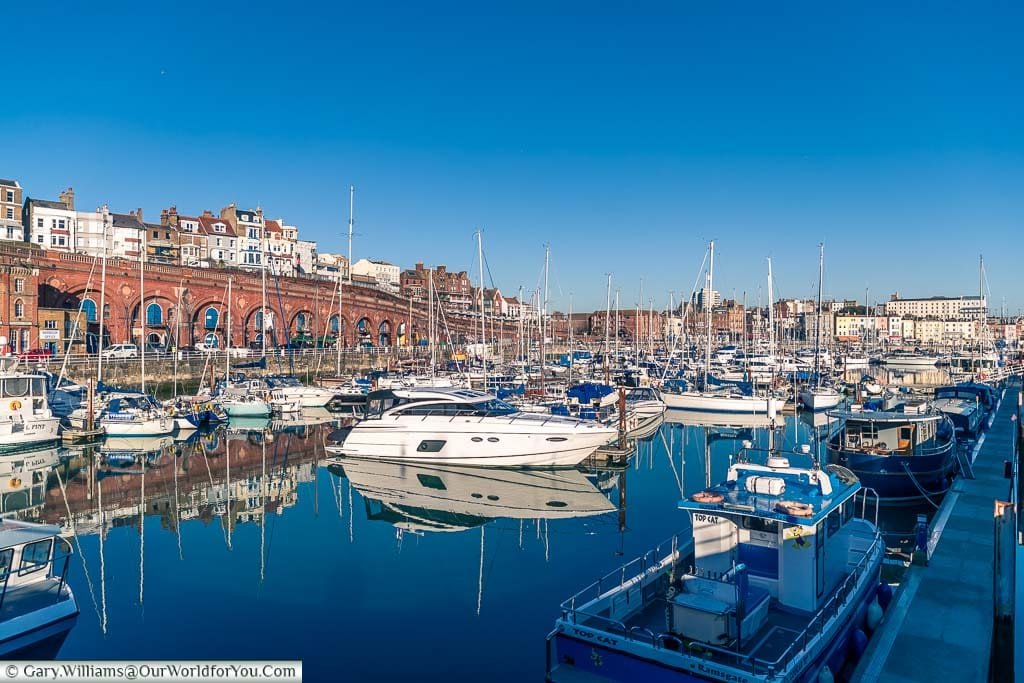 View from one corner of Ramsgate’s Marina across the selection of different boats that take refuge here. This is set against the backdrop of the red brick colonnade that leads down to the Harbour front