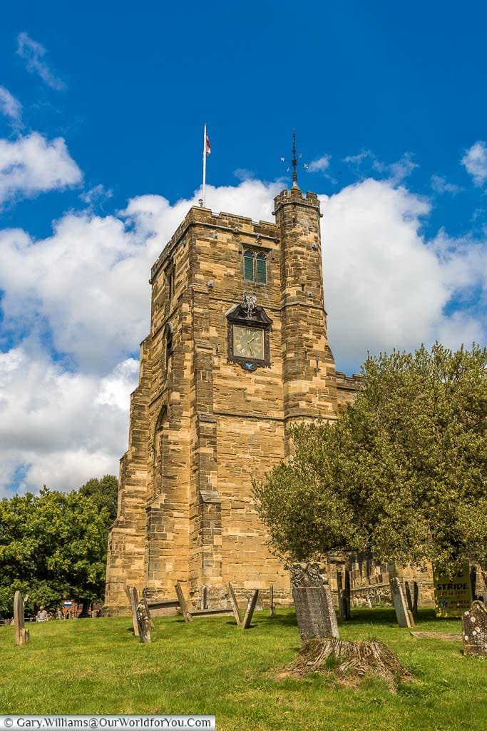 The bell tower and clock face of Saint Dunstan's church in Cranbrook Surrounded by headstones from the graveyard