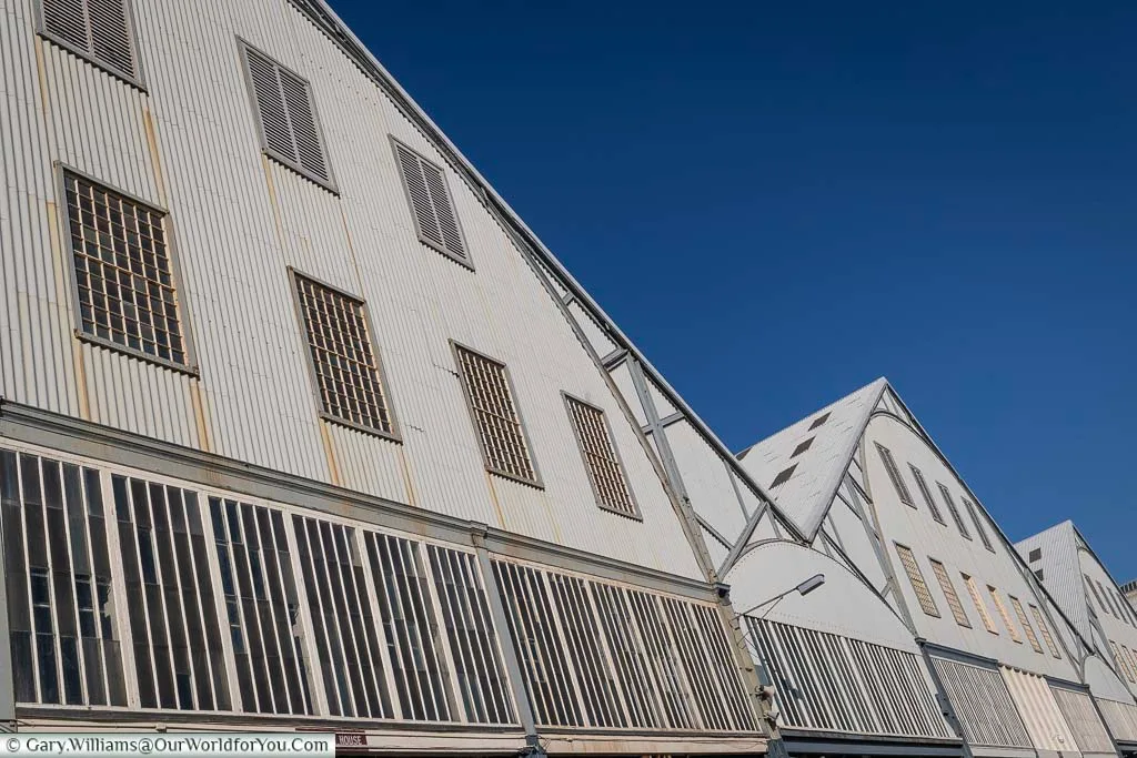 Looking up at the white rooflines of the boathouses of the Historic Dockyard Chatham contracting against a cloudless deep blue sky.