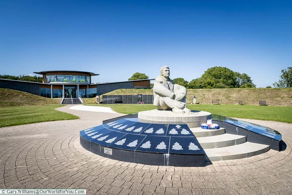 A statue of a pilot, seated on the ground, at the centre of the Battle of Britain Memorial at Capel-le-Ferne.