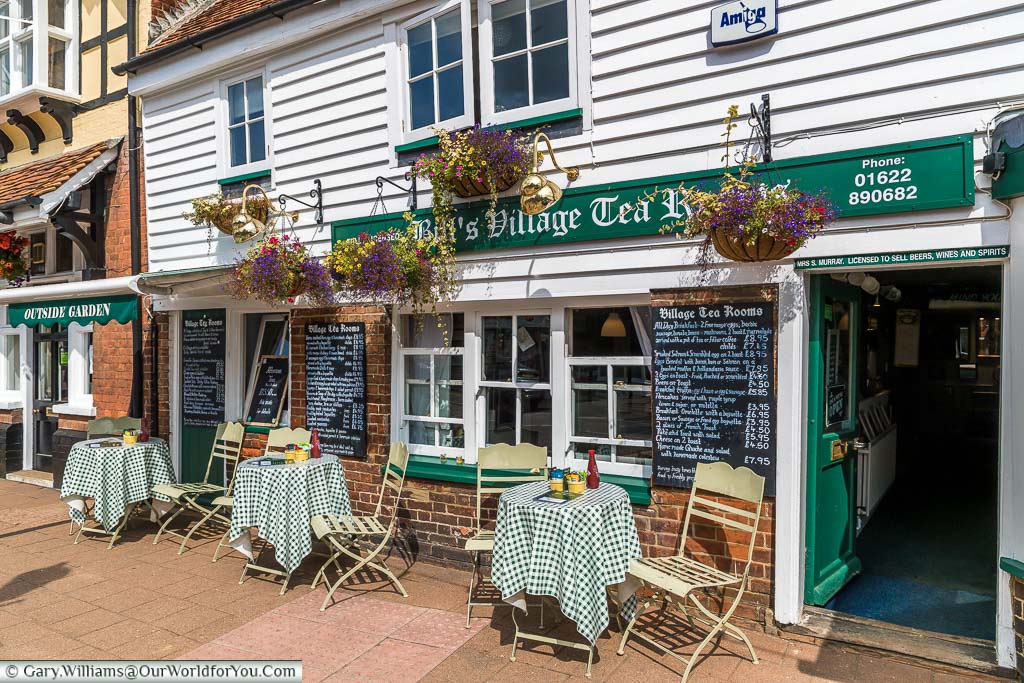 The village tea room shop with 3 tables and chairs outside covered in chequered tablecloths