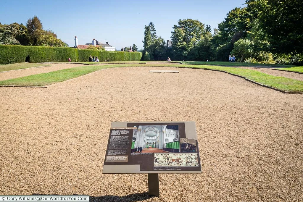 An open-air view of the area where the Battle Abbey high altar once stood. The boundaries are marked out with grass, and an information board gives more details of the original layout.