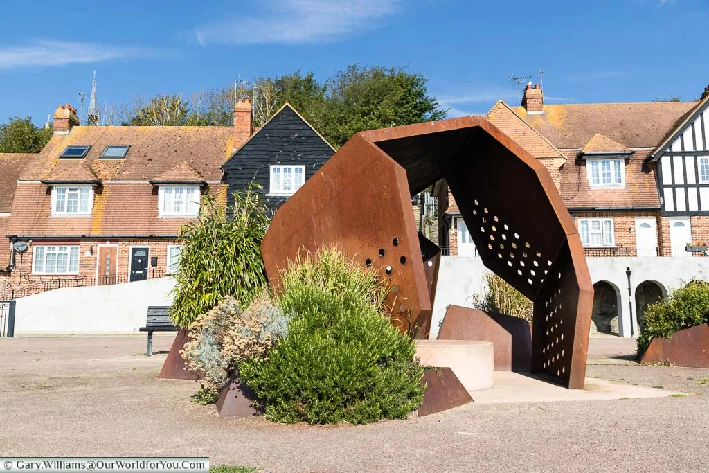 An art installation of a rusted iron sculptural pavilion on the edge of the harbour.
