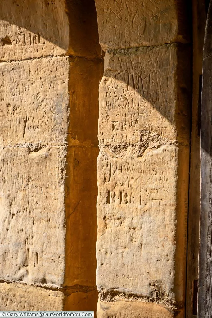 Ancient graffiti carved into the soft sandstone of the arch of the Postern Tower in Bodiam Castle