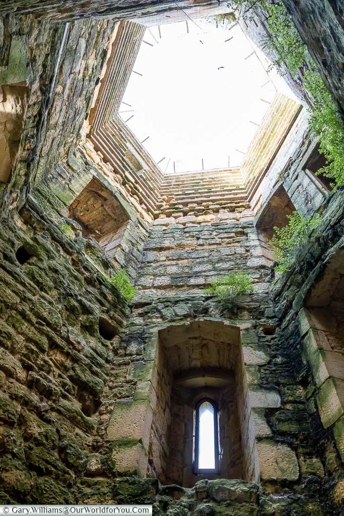 Looking up to the bright sky above the stone southwest tower of Bodium Castle