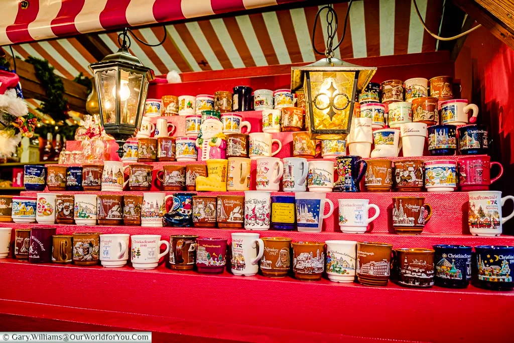 A stall with rows of tiered shelves of glühwein mugs on Nuremberg's Christmas Market