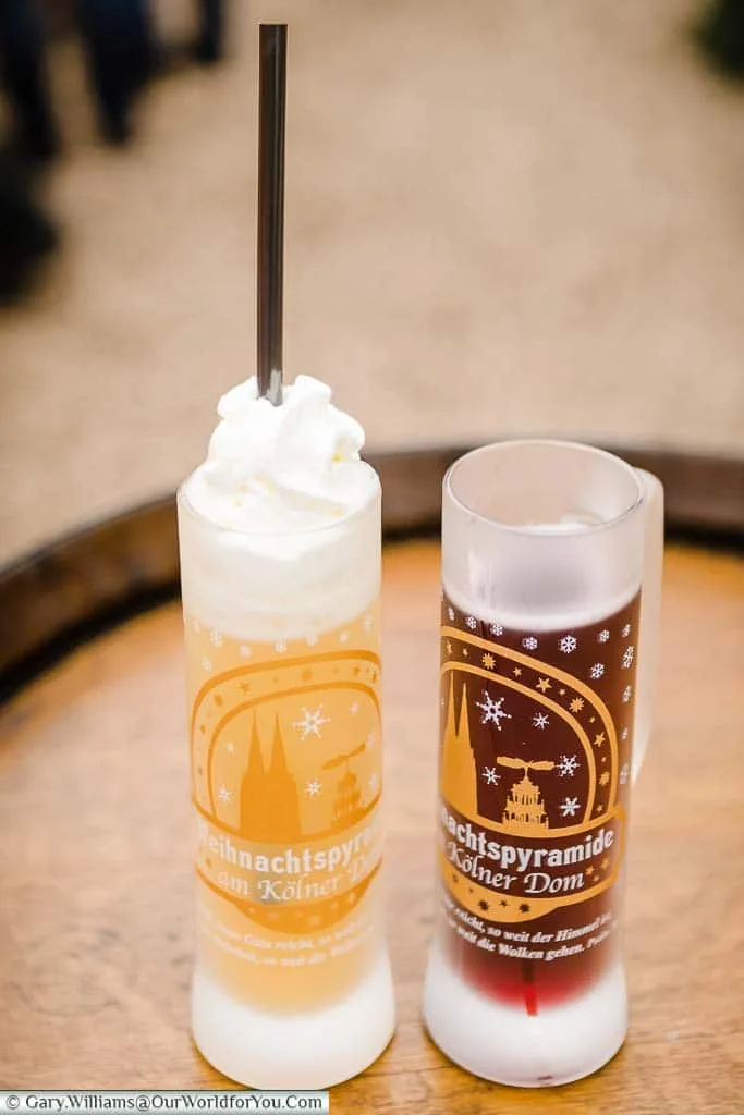 Two long thin glass tankards; one with glühwein, the other with eggnog from Cologne's Dom Christmas Market.