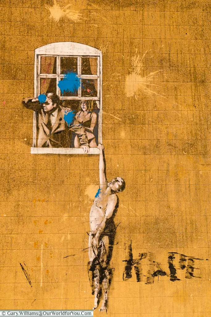The stencilled art work 'Well Hung Lover' by Banksy of a naked man hanging from a window in Bristol