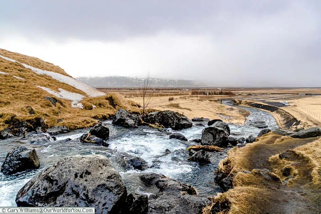 Watching the water flow between black rocks before it falls over the last ledge in the Gluggafoss waterfall in Iceland