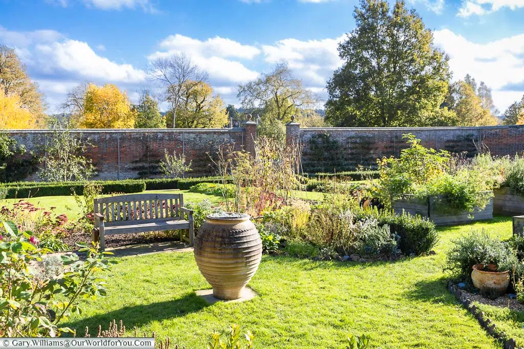 A bench behind a Grecian urn in the centre of the walled garden of Scotney House