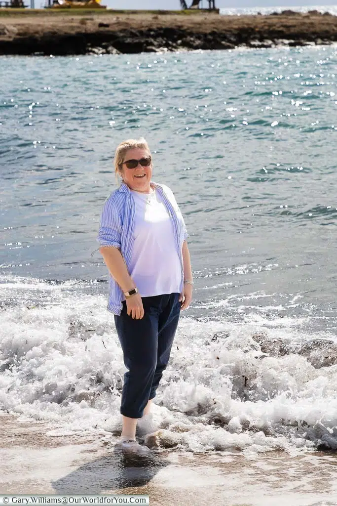 Janis laughing while dipping her toes in the Mediterranean sea in Paphos, Cyprus