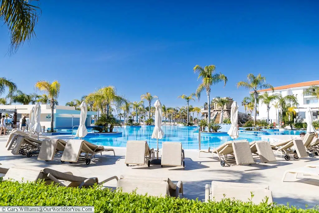 The Olympic Lagoon Resort Paphos poolside under clear blue skies at the start of the day.