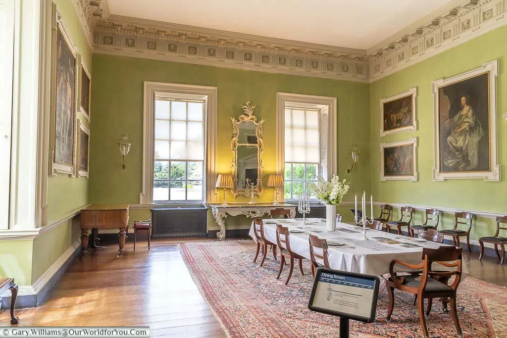 The eight-place dining table in the centre of the sage-coloured, Victorian-styled dining room at Lacock Abbey in Wiltshire.