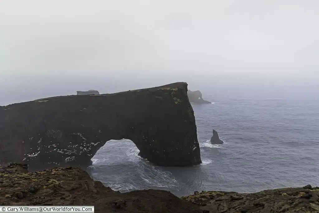 The "Door Hole" rock formation leading out to the rough waters of the Atlantic ocean on a stormy day