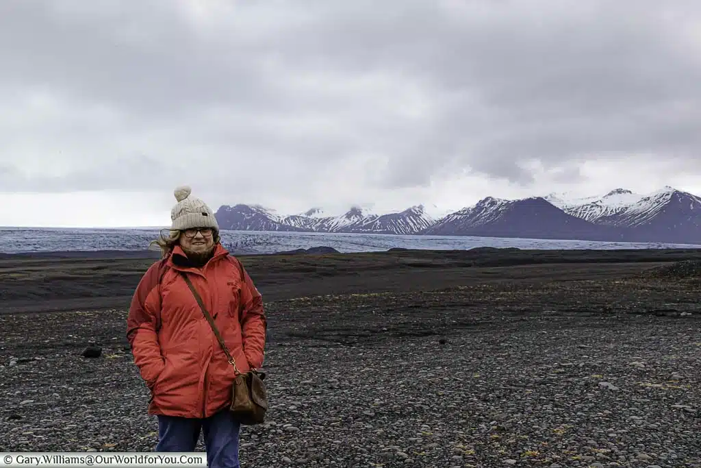 The pale blue ice layer of the Skaftafellsjökull glacier against a backdrop of snow-covered mountains