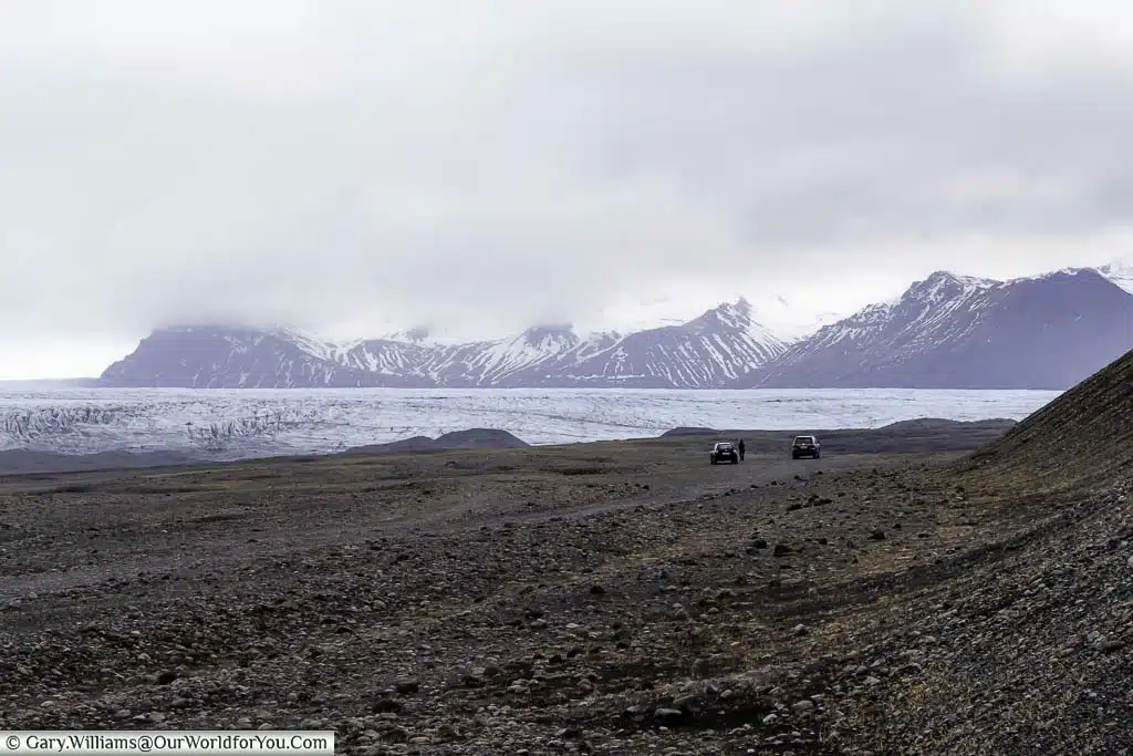 The pale blue ice layer of the Skaftafellsjökull glacier against a backdrop of snow-covered mountains