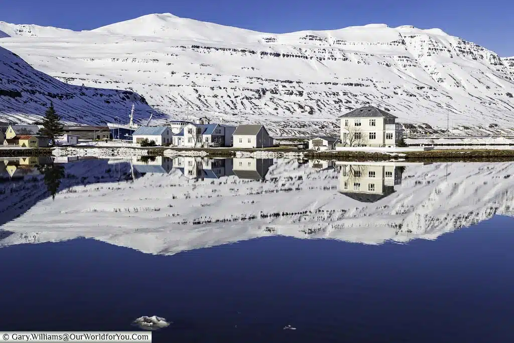 Homes and the mountains behind reflected in a lake in Seydisfjordur, Iceland