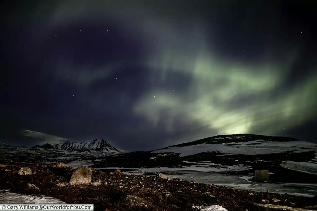 The swirling green colours of the Northern Lights over the mountains just outside ReykjahlÃð in Eastern Iceland