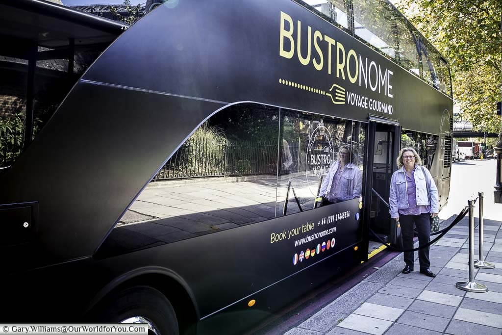 Janis is standing alongside the Bustronome luxury bus on Victoria Embankment just before starting the tour.