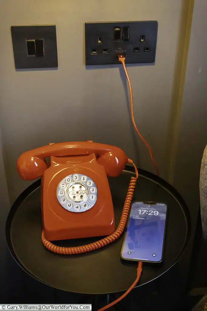 A traditional red telephone below an electrical wall socket that includes a USB port in our king deluxe room at the hotel indigo chester