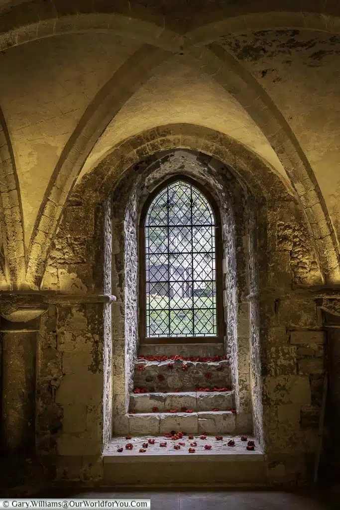 Knitted poppies scattered in a stone window of the medieval crypt of rochester cathedral in kent