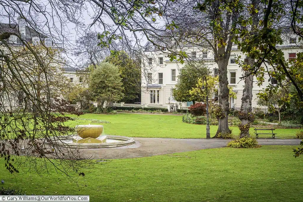 The fountain at the centre of the Dane John Gardens in Canterbury with Georgian homes on the edges.