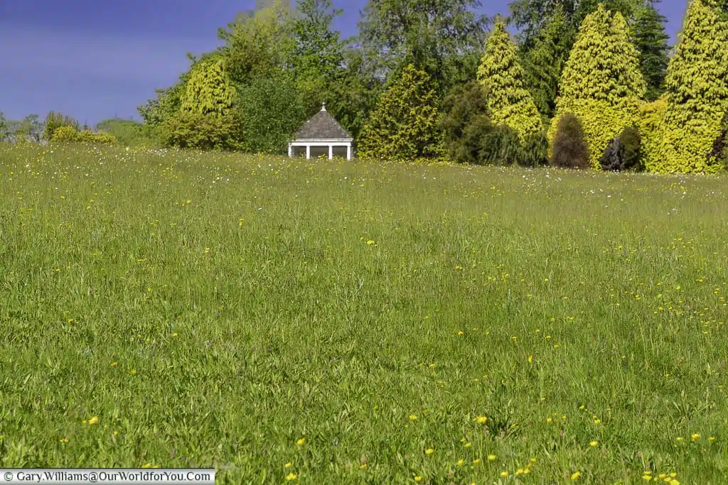 A view across the meadow at the national trust nymans country house and gardens to the memorial shelter to Alfred Messel in the distance.