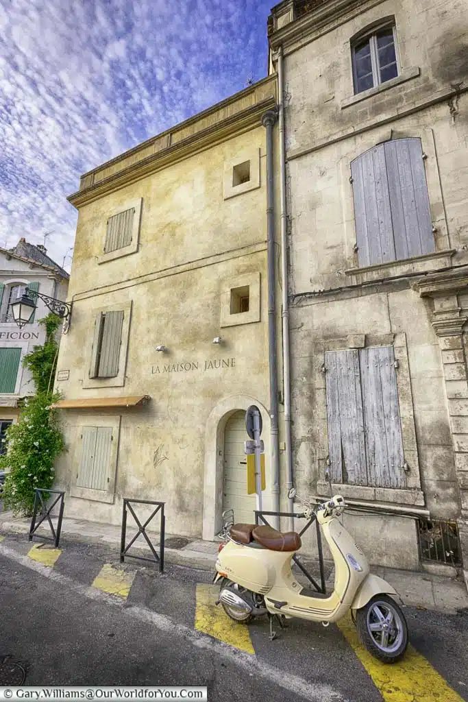 A cream motor scooter parked outside shuttered apartments in the historic centre of Arles in the heart of the Provence region of France