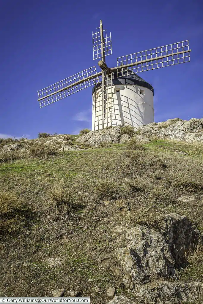 Looking up at an ancient white windmill in consuegra in the rocky landscape of la mancha, spain